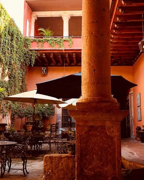 A courtyard with outdoor seating, a column, and a covered area. - Casa Eugenia Hotel (Morelia)