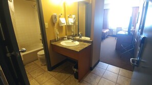 A hotel bathroom with a sink, mirror, and two hair dryers. - The Neighbourhood Inn Express (Bonnyville)