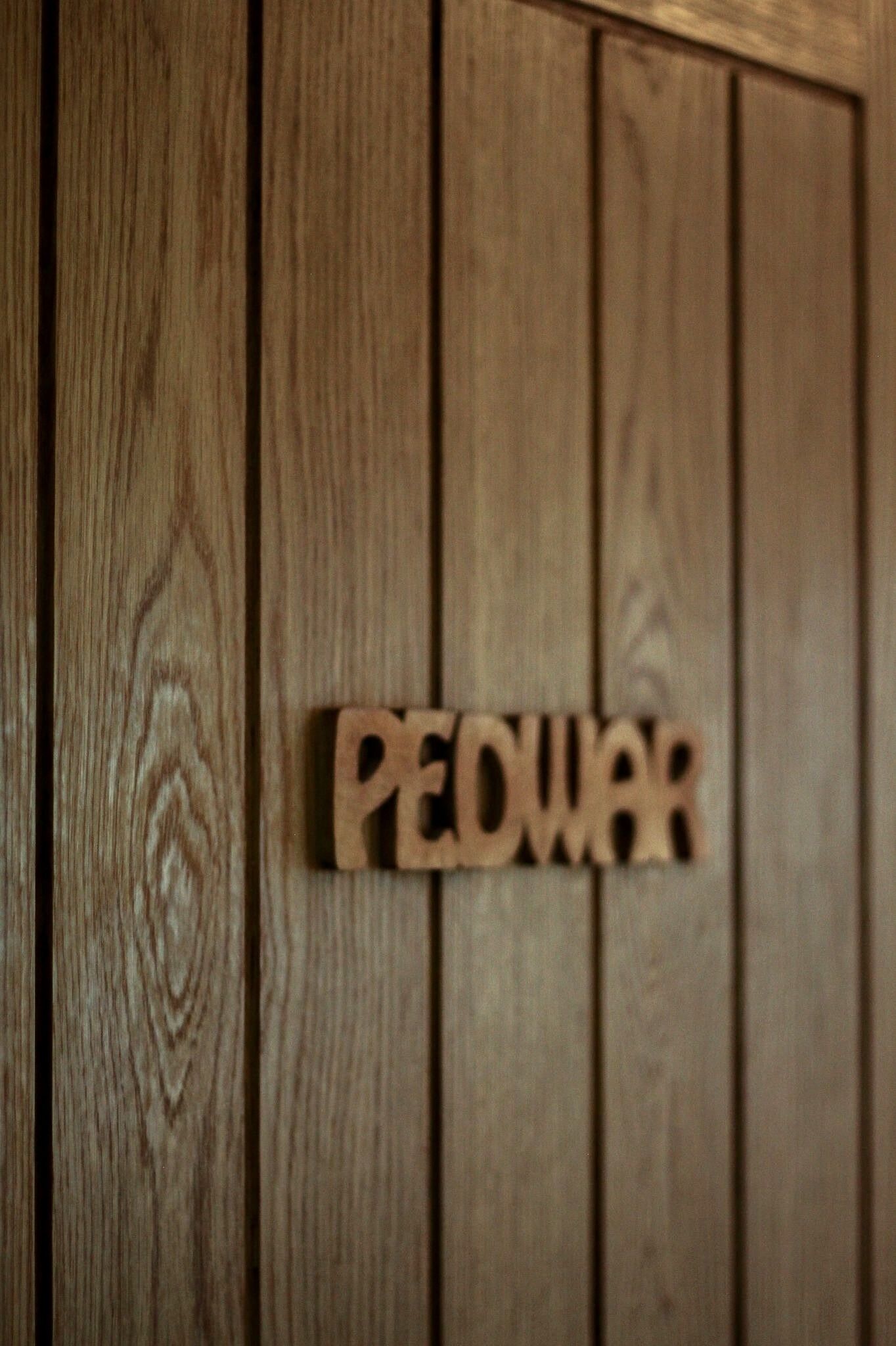 A wooden panel with the word "PEDWAR" mounted on it.