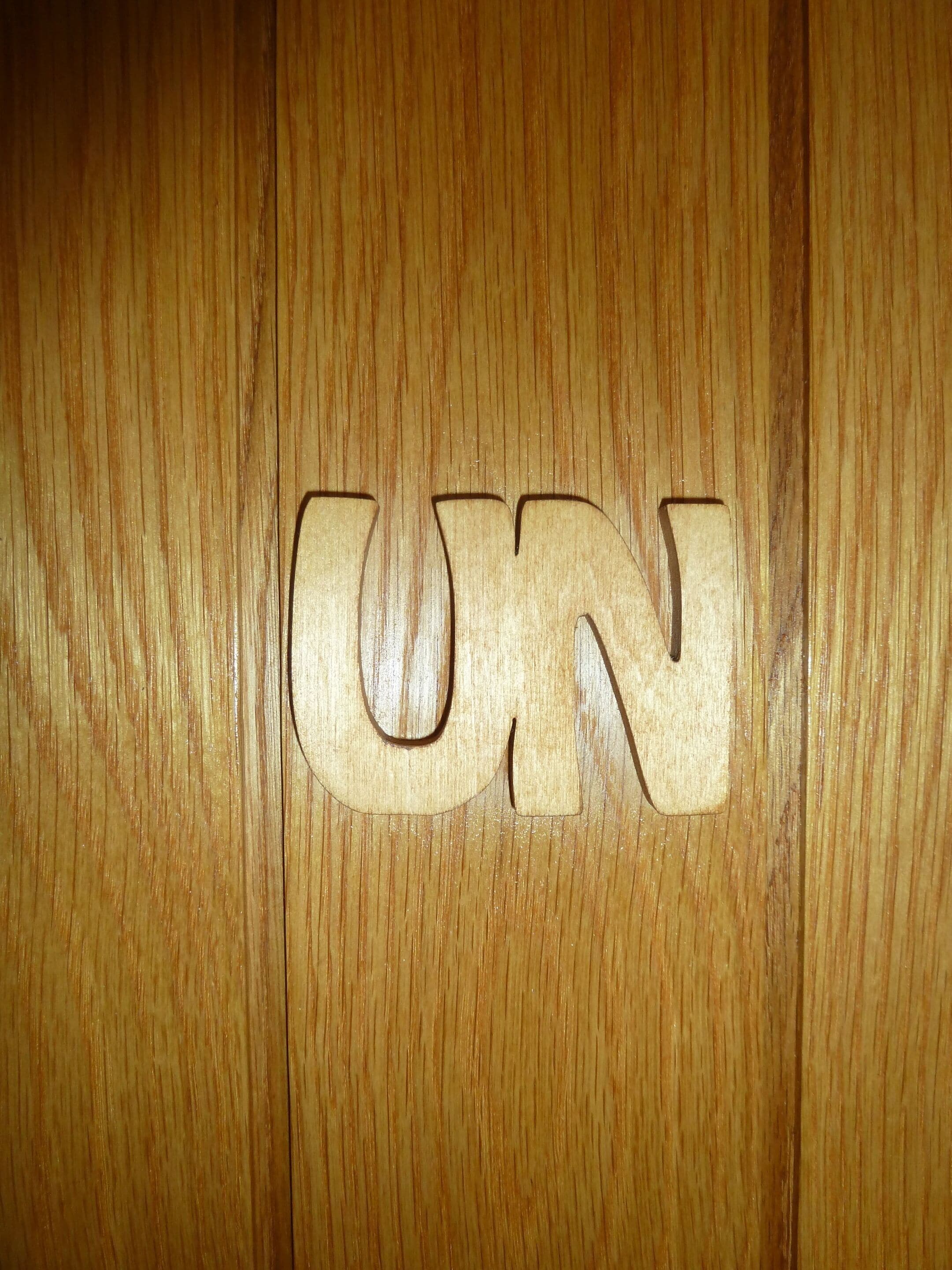 A wooden surface with the letters "UN" carved into it.