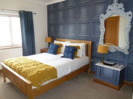 A bedroom with a wooden bed, a large mirror, and a nightstand with a lamp.