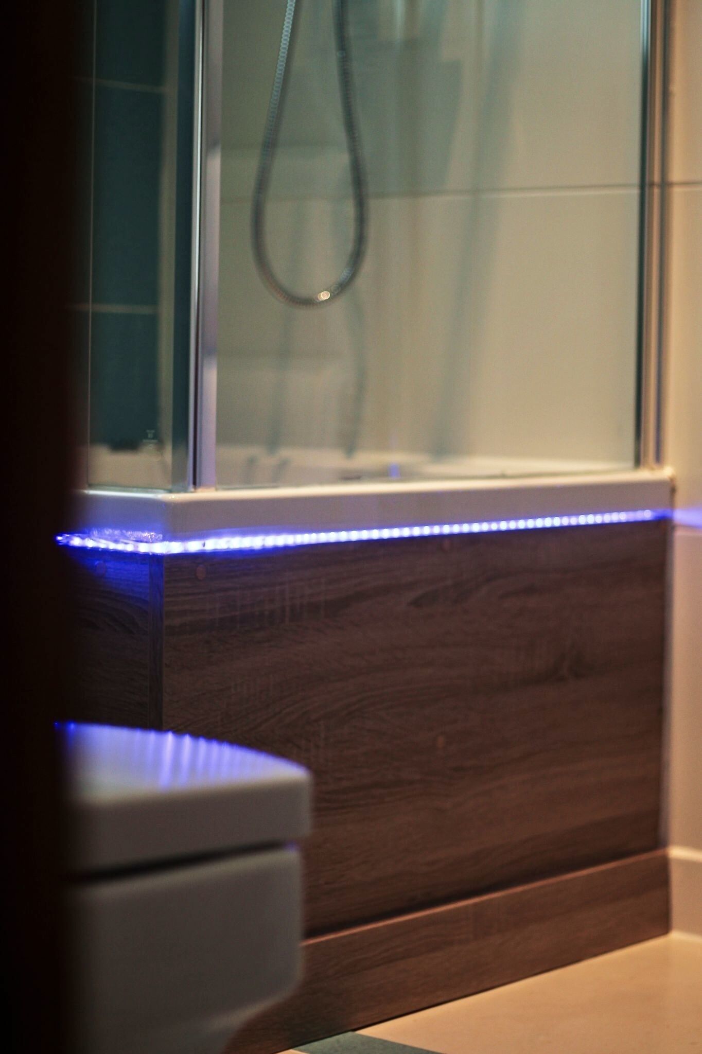 Een badkamer met een douche, een houten wastafelmeubel en een wit toilet.