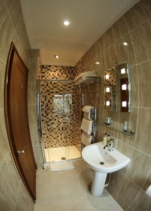Une salle de bain moderne avec une douche à parois de verre, un lavabo blanc et un mur recouvert de carreaux.