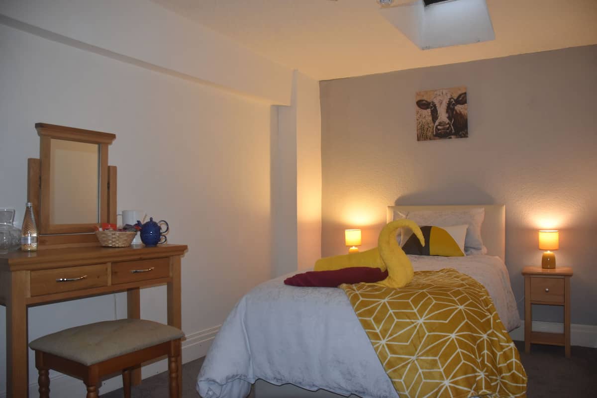 A bedroom with a bed, bedside lamps, a dresser, and a mirror.
