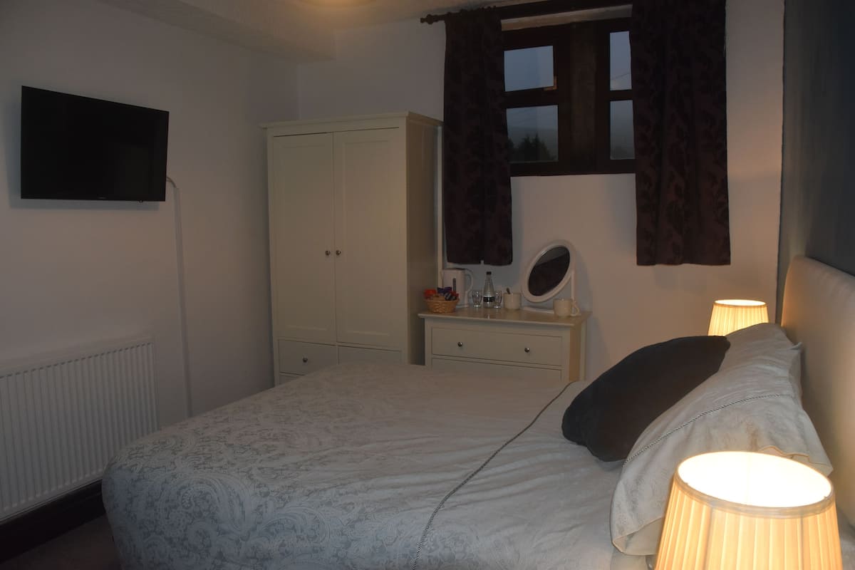 A bedroom with a bed, a dresser, a mirror, and a window with curtains.