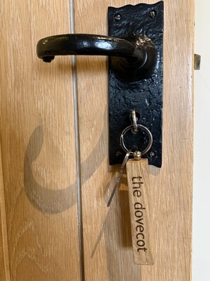 A wooden door with a black metal handle and a keychain with the inscription 'the dovecot.'