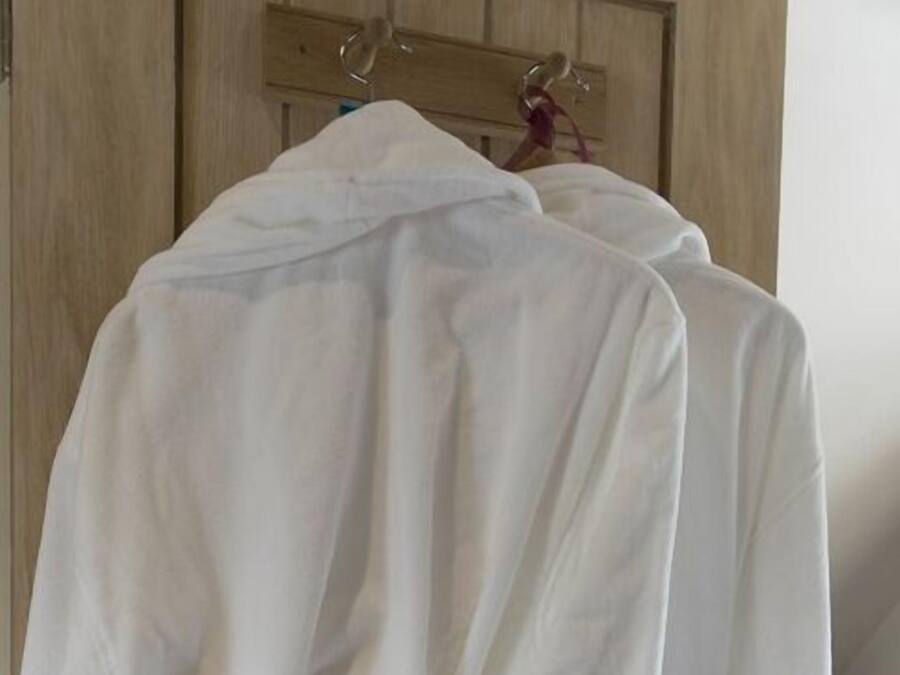 Una puerta de madera con una bata blanca colgada de un perchero.