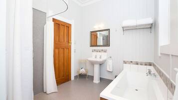 A bathroom with a wooden door, a white sink, a mirror, and a bathtub.