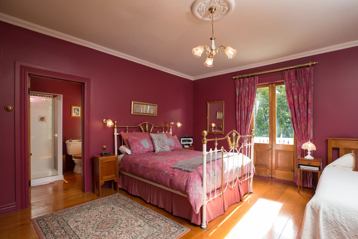 A bedroom with a four-poster bed, a chandelier, and a large window with curtains.