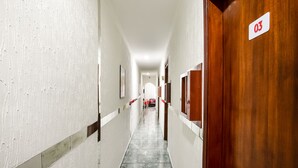 A hallway with white walls, a tiled floor, and a wooden door marked with the number 03. - Hotel Belém (São Paulo)