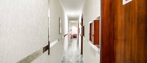 A hallway with white walls, a tiled floor, and a wooden door marked with the number 03.