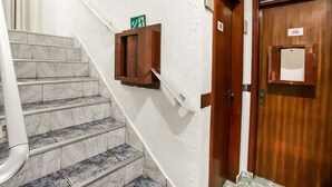A staircase with marble steps and a wooden door with a sign indicating room number 06. - Hotel Belém (São Paulo)