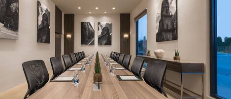 A conference room with a long table, black chairs, and framed pictures on the walls.