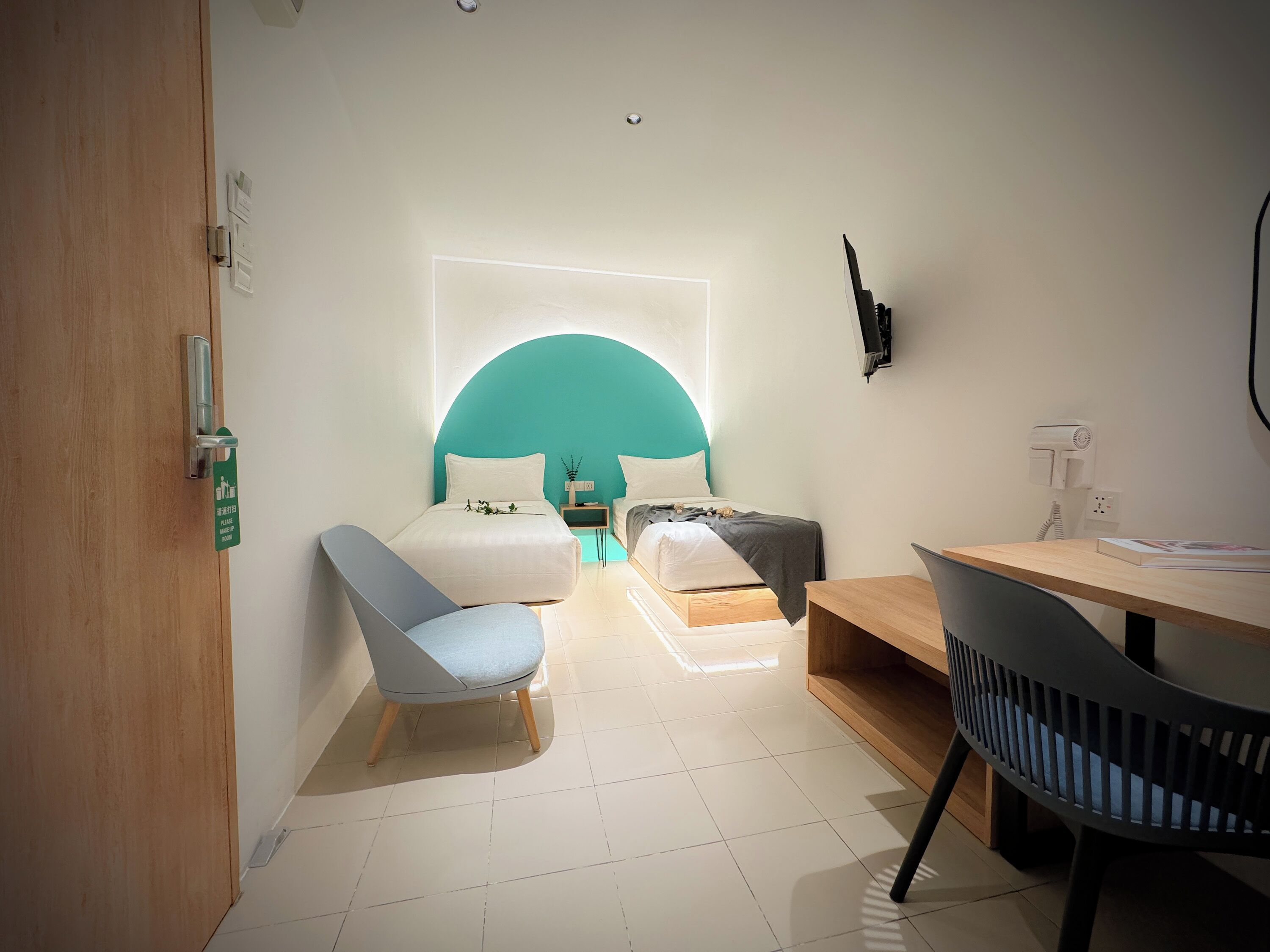 Quarto de hotel moderno com cama, escrivaninha, cadeira e uma pequena mesa.