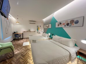 Une chambre d’hôtel avec deux lits, un bureau, une chaise et des œuvres d’art accrochées aux murs.