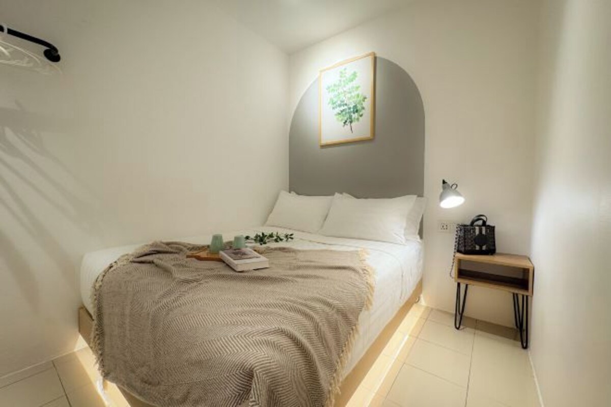 A neatly arranged bedroom with a bed, bedside table, and a wall-mounted picture.