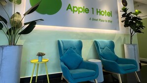 A reception area with a sign reading "Apple 1 Hotel" and two blue armchairs. - Apple 1 Hotel Queensbay (George Town)