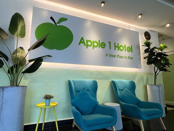 A reception area with a sign reading "Apple 1 Hotel" and two blue armchairs. - Apple 1 Hotel Queensbay (George Town)