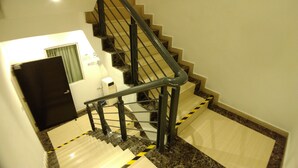 A staircase with a handrail, carpeted steps, and a door with a window. - Apple 1 Hotel Queensbay (George Town)