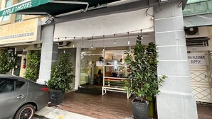 The exterior of Apple 1 Hotel with a green awning, a visible entrance, and potted plants. - Apple 1 Hotel Queensbay (George Town)