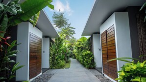 A modern building with a concrete pathway flanked by lush greenery and wooden doors. - Abia Villa and Suite Legian (Legian)