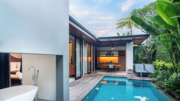 A modern outdoor pool area with a built-in jacuzzi, wooden deck, and lush greenery. - Abia Villa and Suite Legian (Legian)
