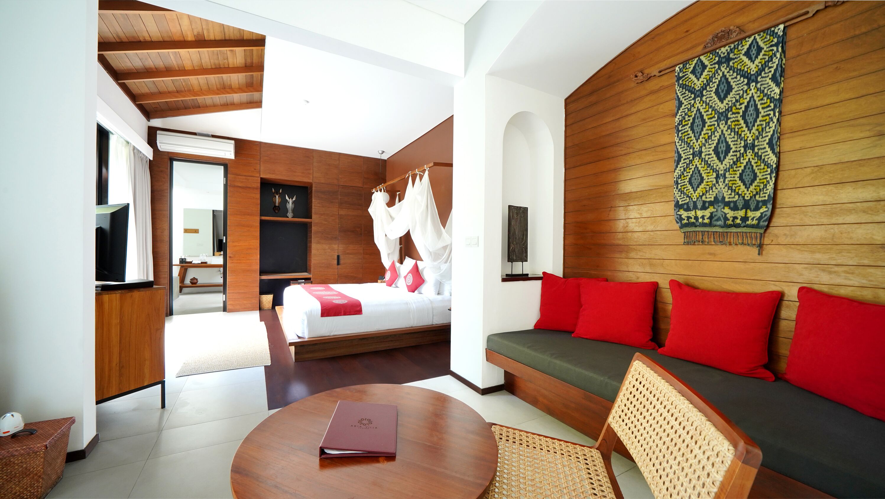 A modern hotel room with a bed, a sofa, a TV, and a large window.