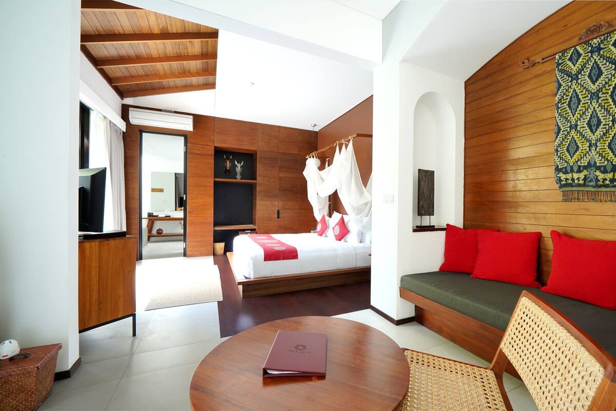 A modern hotel room with a bed, a sofa, a TV, and a large window.