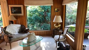 Una habitación acogedora con un sofá estampado de leopardo, una mesa de centro de cristal y una escultura de caballo. Hay dos lámparas, un cuadro enmarcado y una ventana con vistas a zonas verdes.