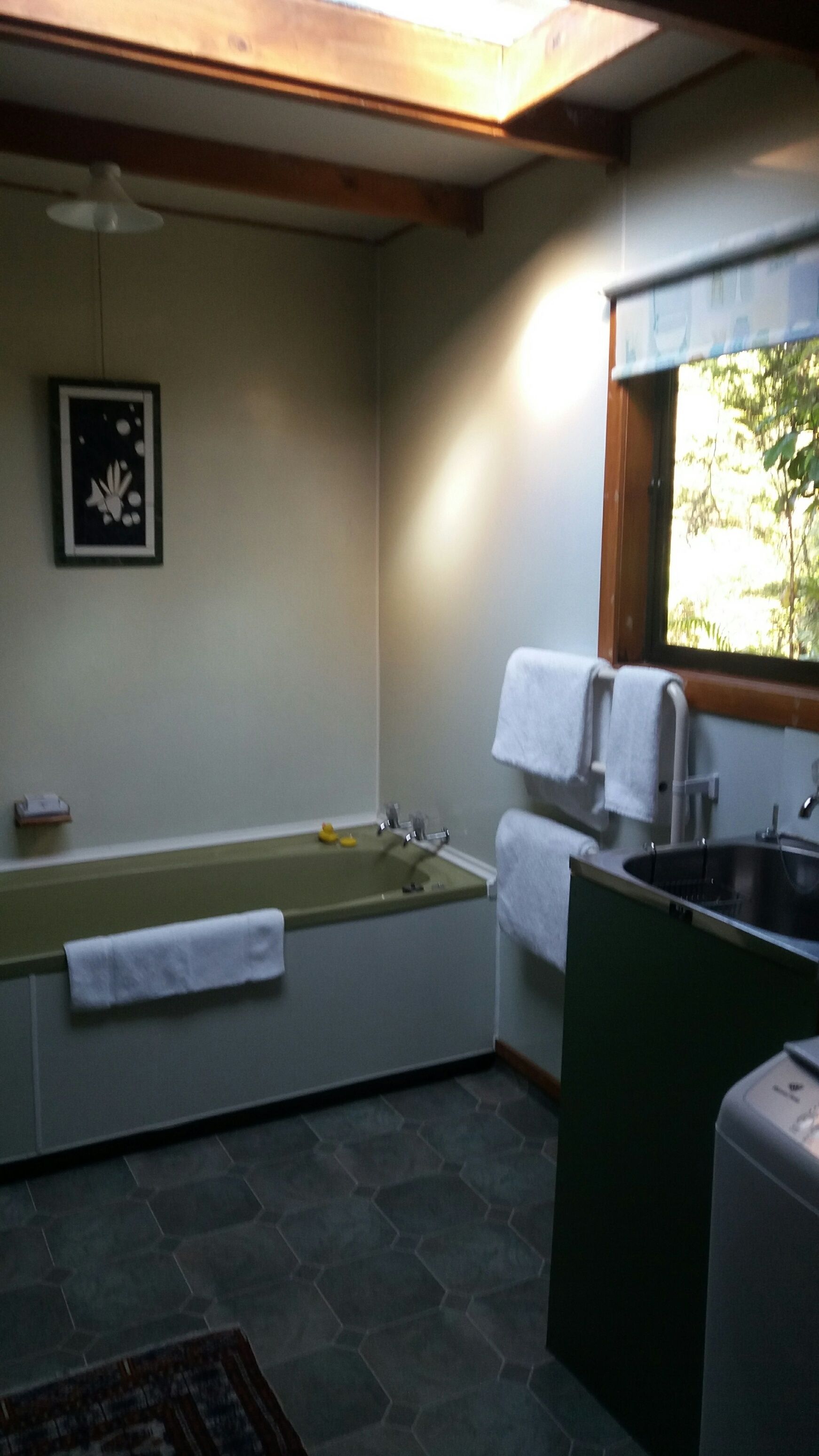 Une salle de bain avec une baignoire, un lavabo et une fenêtre.