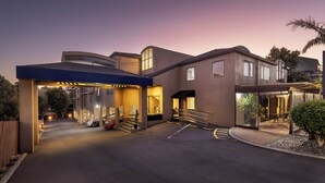 A modern building with a covered entrance, a staircase, and a parking area. - Edit Auckland Greenlane (Auckland)