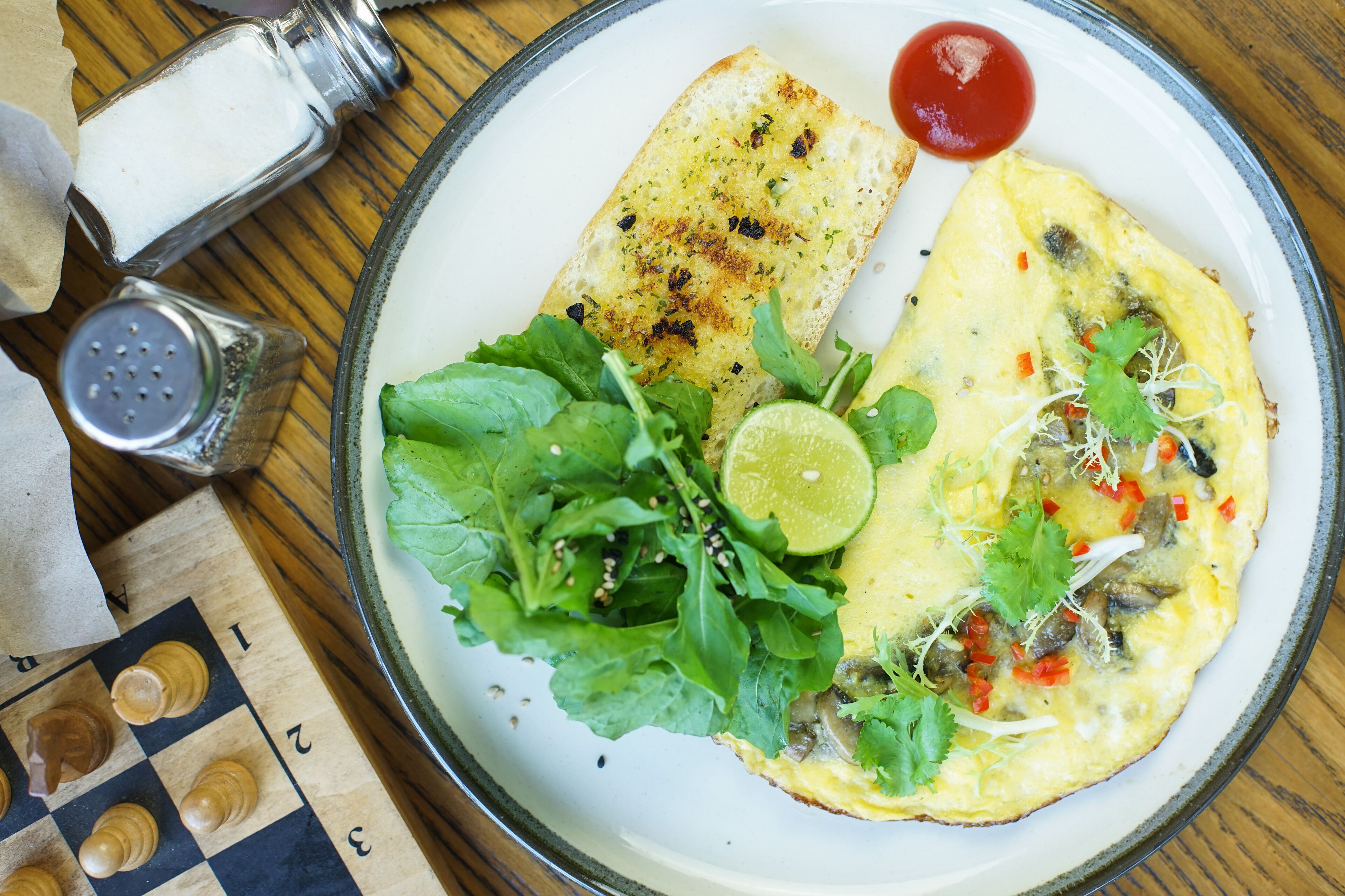 Een bord met een omelet, een sneetje toast en een salade.