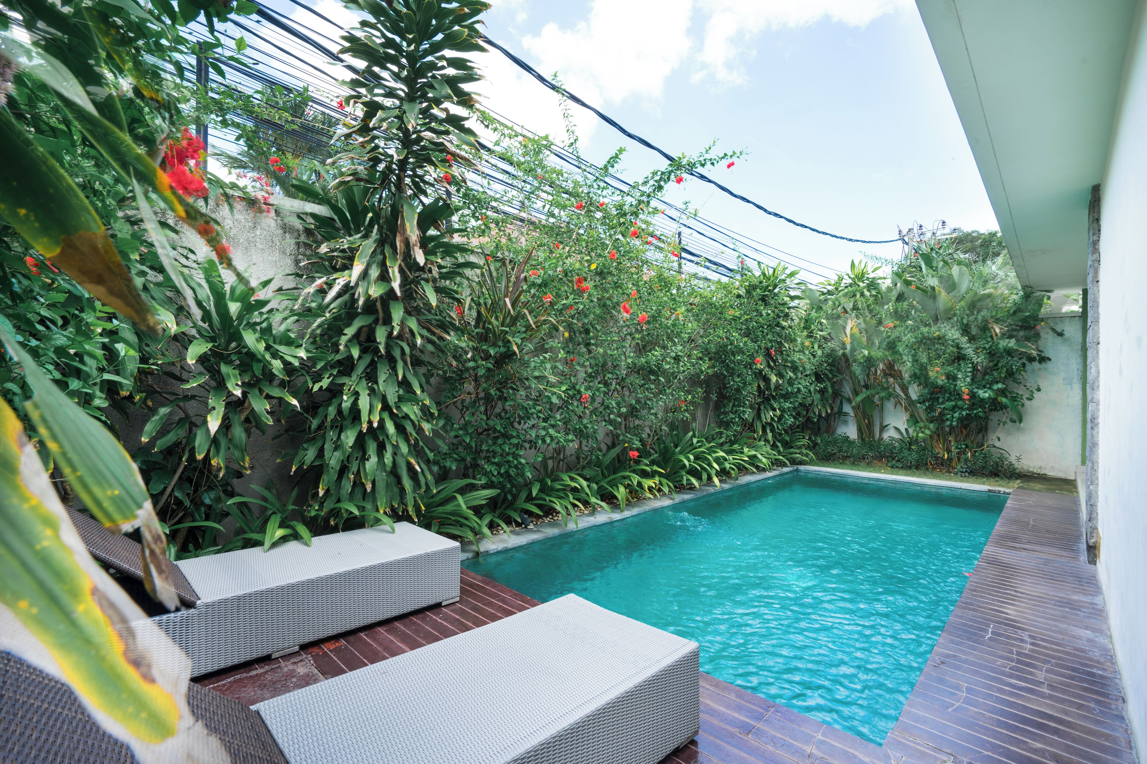 A swimming pool with a wooden deck and white lounge chairs.