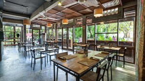 Ein geräumiges Restaurant mit hohen Decken, großen Fenstern und Holztischen und -stühlen.