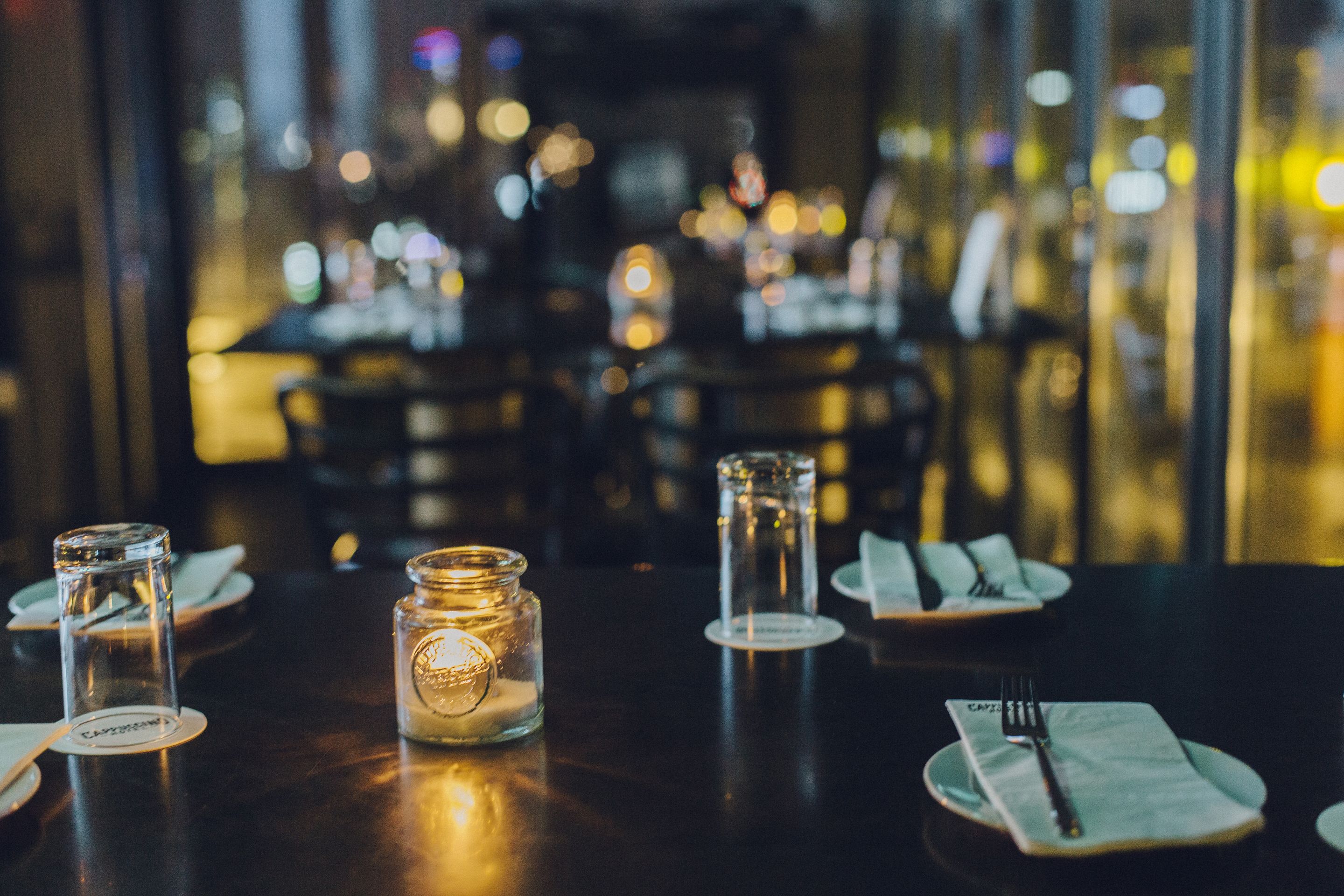 A dining table set with candles, plates, and cutlery.