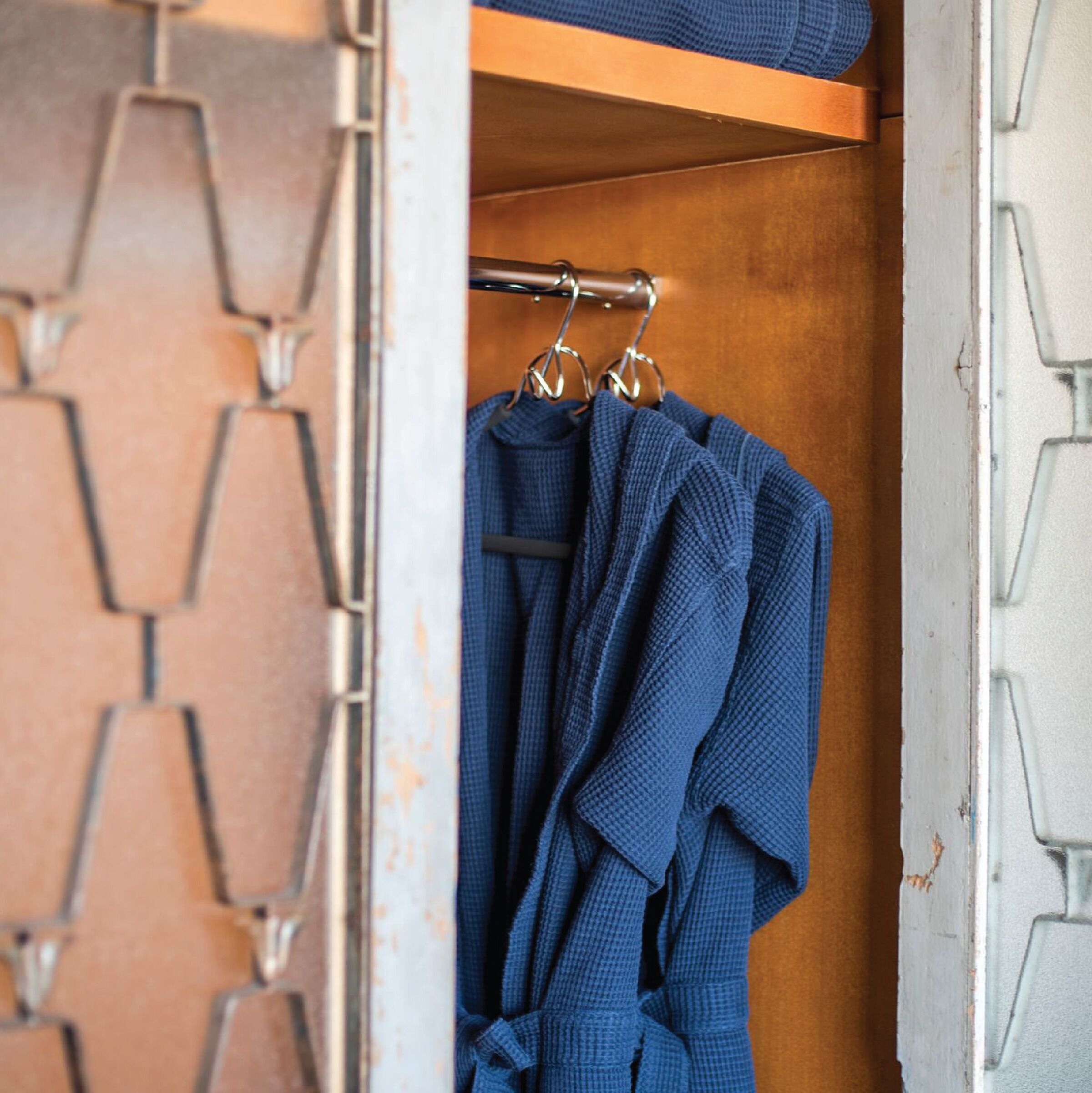 A closet with a wooden interior and a geometric patterned wall.