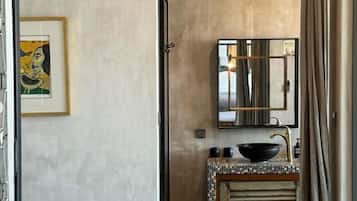 Un baño con lavamanos, espejo y un banco azul.