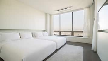 A modern hotel room with a large bed, a view of the city, and a window with curtains.