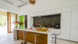Una cocina moderna con una isla central, taburetes de bar y vistas al exterior.