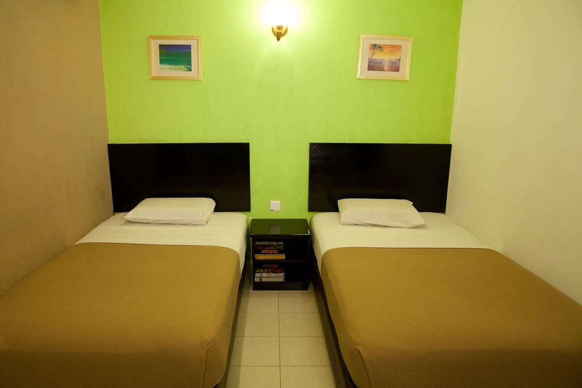 A twin room with two beds, a nightstand, and a wall-mounted light.