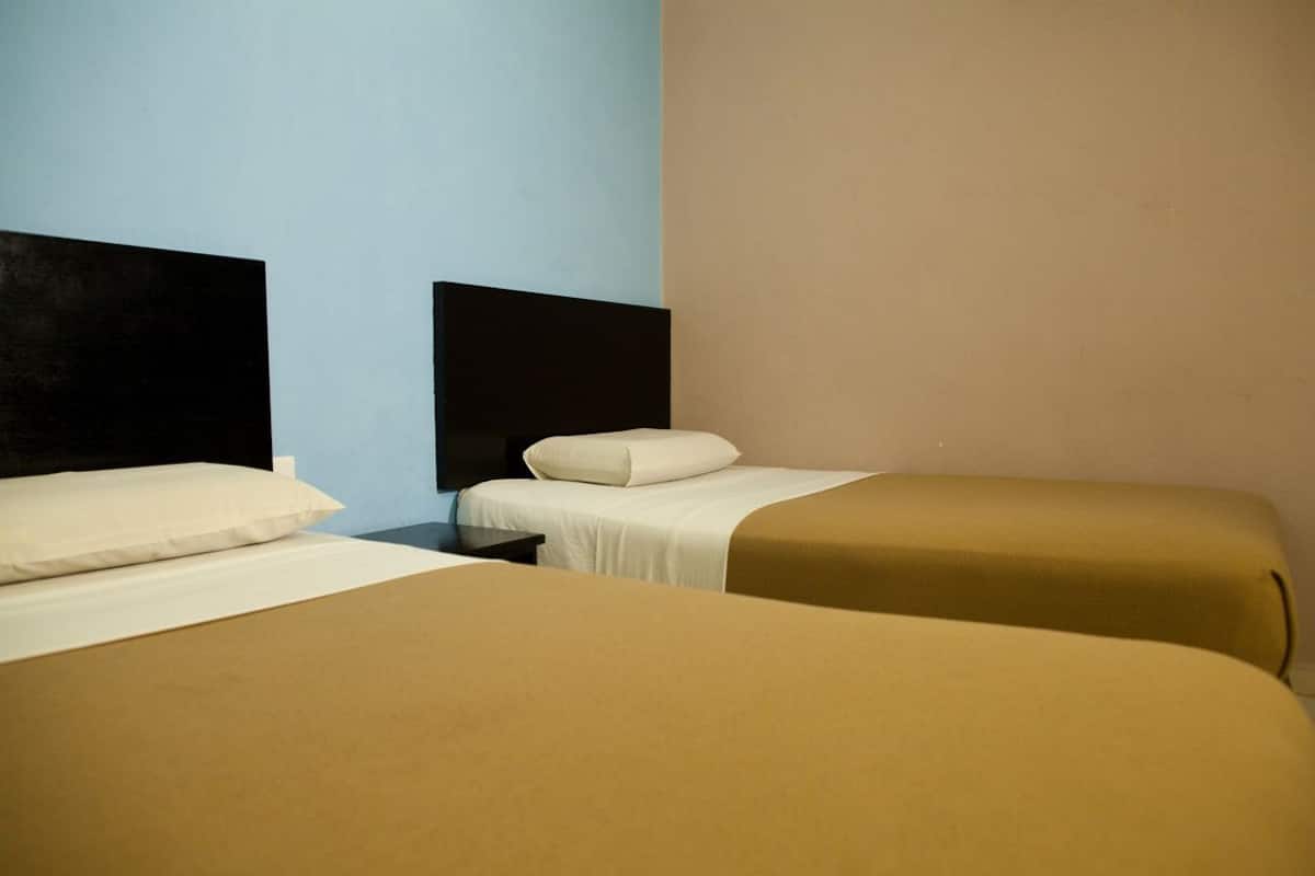 A hotel room with two beds, each with a headboard and a pillow.