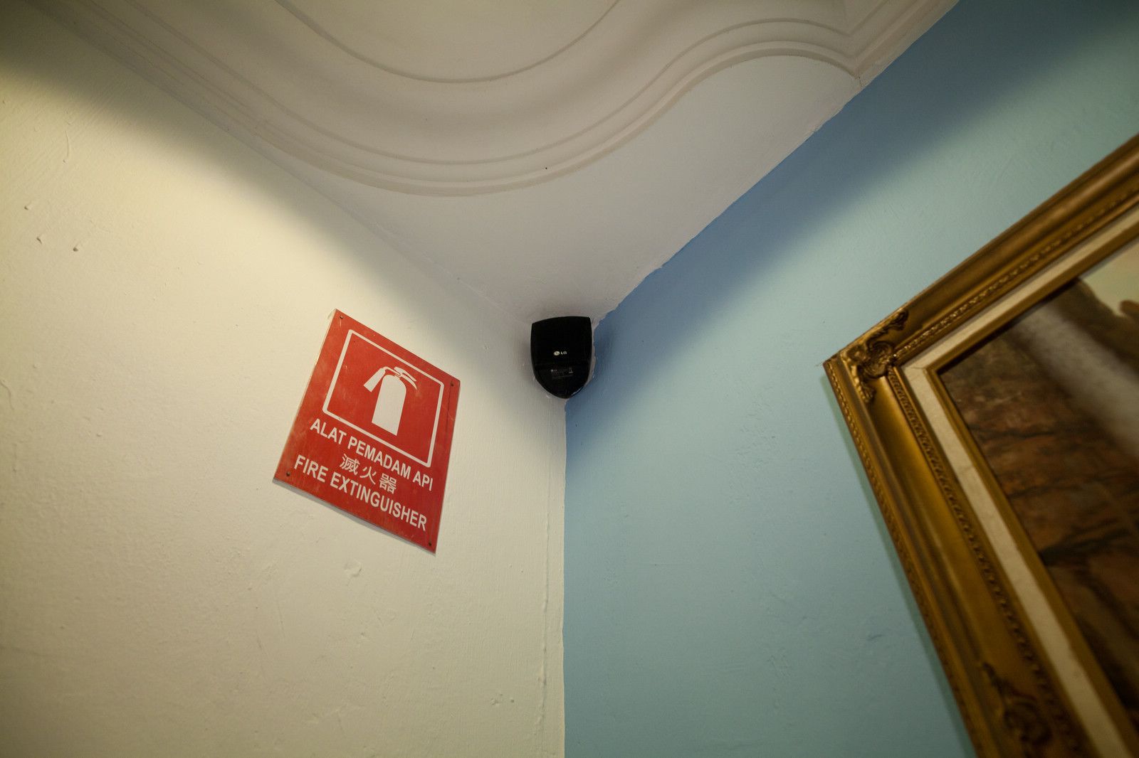 A fire extinguisher sign in a room with a white ceiling and light blue walls.