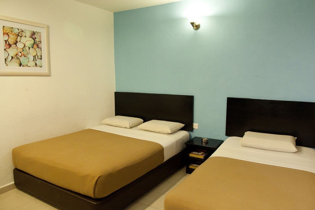 A hotel room with two beds, a nightstand, and a framed picture on the wall.