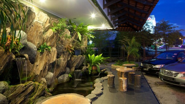 A rock garden with a small pond, wooden benches, and a car parked nearby. - Hotel Ria (Johor Bahru)