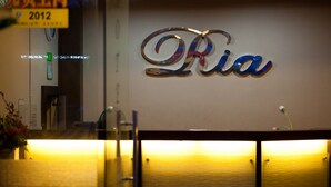 A reception desk with a wall-mounted sign that reads "Ria". - Hotel Ria (Johor Bahru)