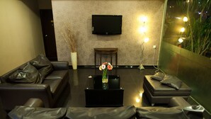 A modern lounge with leather sofas, a flat-screen TV, and a decorative vase with flowers. - Hotel Ria (Johor Bahru)
