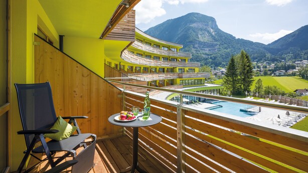 A balcony with a view of a mountain, a pool, and a dining table with fruit and drinks. - DAS SIEBEN ****s - Adults Only (Bad Haering)