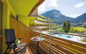 A balcony with a view of a mountain, a pool, and a dining table with fruit and drinks. - DAS SIEBEN ****s - Adults Only (Bad Haering)