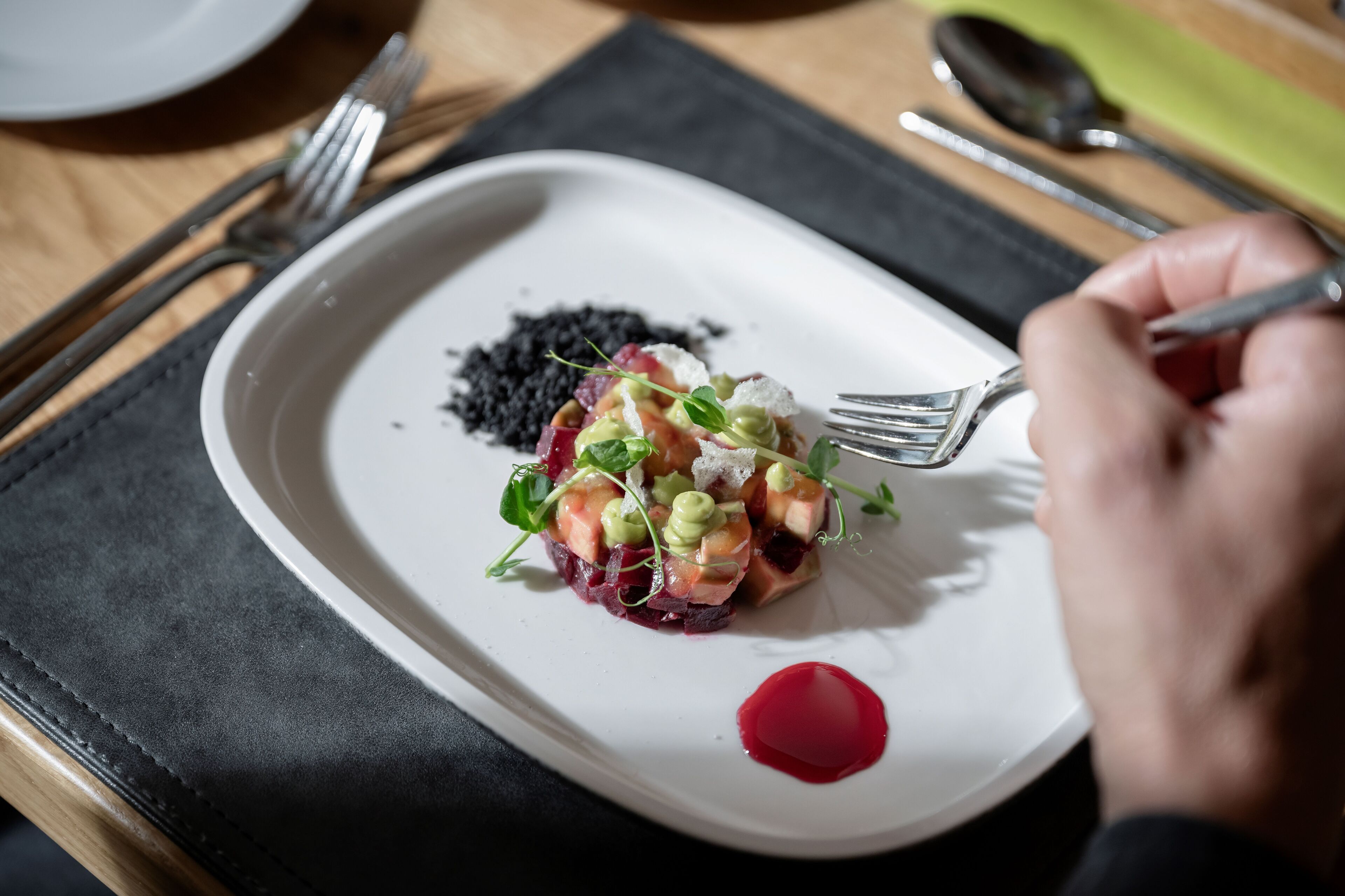 Un plato blanco con una porción de comida, un tenedor y una cuchara sobre una mesa.