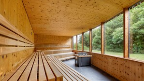 A wooden interior with benches and a table, large windows, and a view of greenery outside. - DAS SIEBEN ****s - Adults Only (Bad Haering)